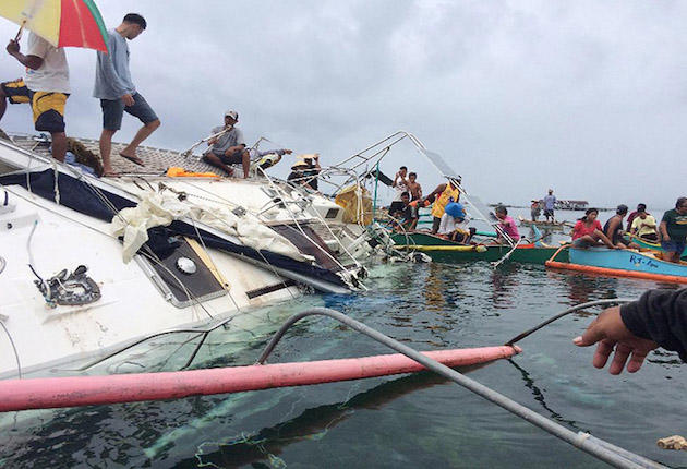 In this Saturday Feb.27, 2016, photo provided by Barobo Police Station of the Philippine National Police, police, coast guard and Filipino fishermen inspect a yacht near the shore off Barobo township, Surigao Del Sur province in southeastern Philippines. Philippine police say they're trying to determine the identity and cause of death of a sailor who was found dead while sitting slumped on a table by the radio of a wayward yacht found adrift in the Pacific Ocean. (Christopher Templanza/PNP Barobo Station via AP) MANDATORY CREDIT