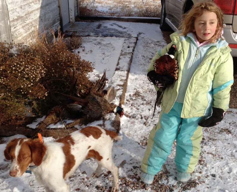 young hunter with pheasant and brittany dog