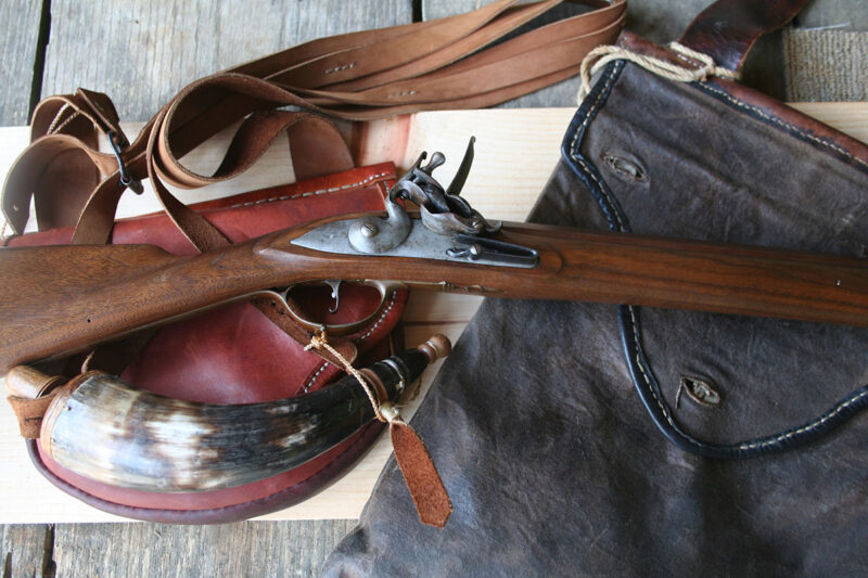 A traditional flintlock rifle and accessories in the autumn woods